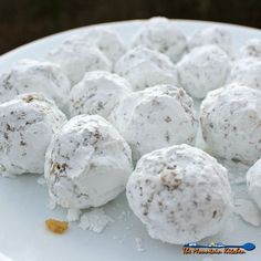 a white plate topped with snowballs covered in powdered sugar