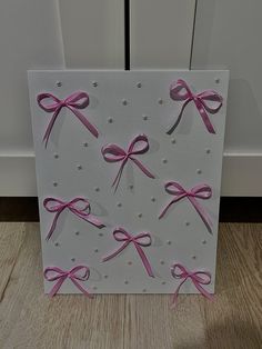 a card with pink bows on it sitting on a wooden floor next to a door