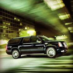 a black suv driving down a city street at night