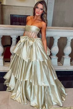 a woman in a gold dress standing on stairs with her hand on her hip and looking at the camera