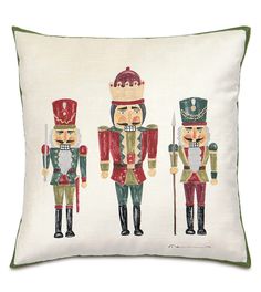 three nutcrackers on a white pillow with green trim, one in red and the other in green