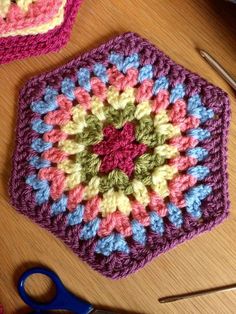 a crocheted hexagon sits on a table next to scissors