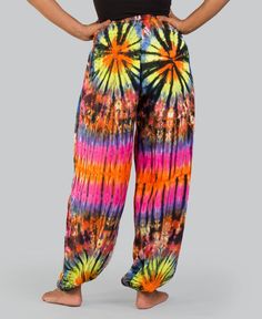 a woman in black top and colorful tie dye pants with her hands on her hips