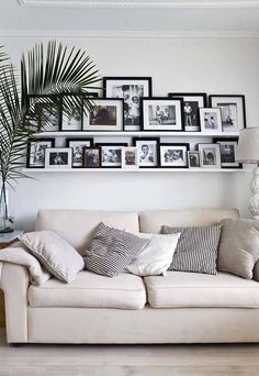 a white couch sitting in front of a wall filled with pictures and framed photos on it