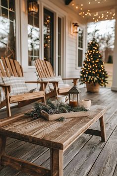 a wooden table sitting on top of a porch next to two chairs and a christmas tree