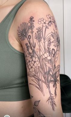 a woman's arm with flowers and leaves tattooed on the back of her shoulder