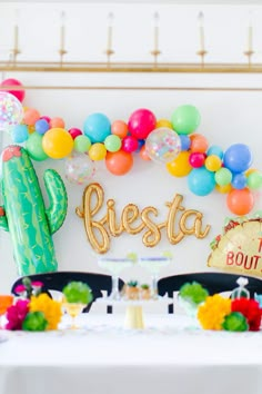 a table topped with balloons and a sign that says fiesta next to a large cactus