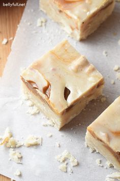 three pieces of dessert sitting on top of a piece of paper next to some nuts