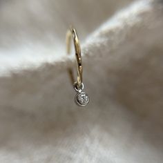 These is a  super delicate 1mm wide sleeper huggie style hoop in solid 9ct yellow gold. It has a subtle hammered texture which really catches the light.  Hanging below the hoop is a 2mm natural genuine bright white diamond charm made in solid platinum.  These hoops are great if you want a subtle look when worn alone and they also stack so well in a curated ear look.  If you require more of this item than is showing as available to purchase please send me a message and I can advise on if I have more available.  All of my items are handmade by myself in my workshop in Surrey, England.  They come well packaged in a branded gift box and would make a lovely gift.  If you like one of my designs but would rather it in a different metal or gemstone please send me a message as I may well be able to White Gold Stackable Huggie Jewelry, Stackable White Gold Huggie Earrings, Minimalist Sterling Silver Hoop Earrings With Single Diamond, Yellow Gold Sterling Silver Huggie Earrings With Single Diamond, Dainty Small Hoop White Gold Jewelry, Tiny White Gold Huggie Jewelry, Silver Hoop Earrings With Single Diamond As Gift, Tiny White Gold Huggie Earrings, Dainty 14k White Gold Hoop Earrings