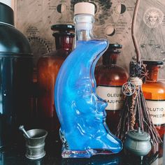 a blue glass bottle sitting on top of a table next to other bottles and jars