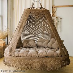 a bed made out of wicker with pillows on the bottom and sides, hanging from a rope