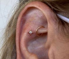 a person with ear piercings on their ears is wearing a gold star and moon ring