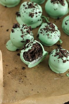 there are many green desserts with chocolate chips on top and frosting in the middle