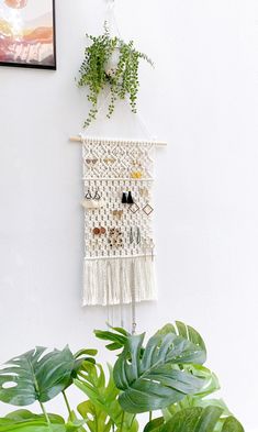 a wall hanging with earrings and plants on it