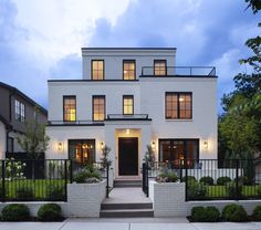 a white brick house with black iron fence and gated in area around the front door