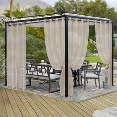 a gazebo with curtains over it on a wooden deck