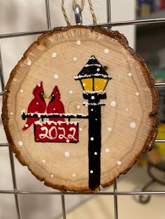 a piece of wood with two birds on it hanging from a wire fence next to a lamp post