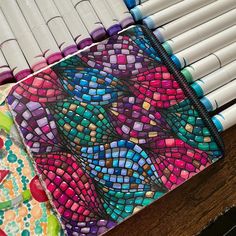 several different colored pencils sitting next to each other on top of a wooden table