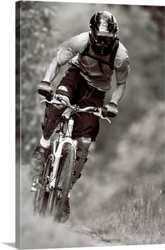 a man riding on the back of a bike down a dirt road with trees in the background