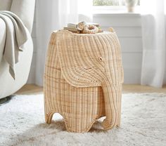 an elephant shaped wicker stool on carpet in front of window with white rugs