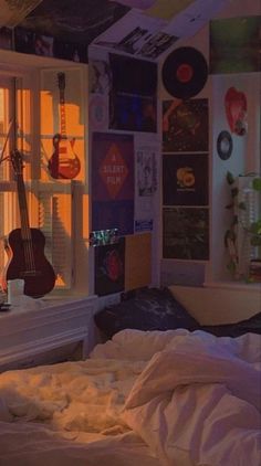 a bedroom with a guitar on the wall and lots of clutter all around it