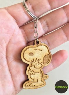 a hand holding a wooden keychain with a cartoon character on it