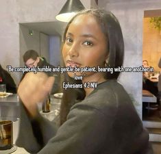 a woman sitting at a table with a cup in her hand and a quote on it