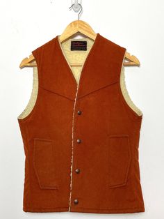 This vest has a few small marks on the back side and slight piling along the sherpa lining. (see last two photos for flaws) Measurements  Pit to pit: 17 inches  Top to bottom: 24 inches Rugged Fall Vest Outerwear, Rugged Fitted Vest Outerwear, Vintage Winter Vest Outerwear, Rugged Brown Vest Outerwear, Classic Winter Vest With Snap Buttons, Brown Rugged Vest For Winter, Rugged Brown Winter Vest, Brown Rugged Winter Vest, Sleeveless Western Winter Outerwear