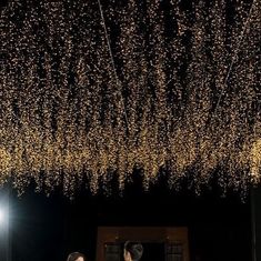 two people standing in front of a ceiling covered with lights