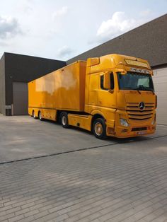 a yellow semi truck parked in front of a building