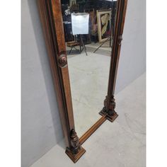 a large wooden mirror sitting on top of a white floor next to a gray wall