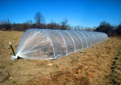 an image of a large greenhouse in the middle of a field that is covered with plastic