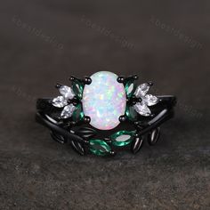 an opal and white topazte ring with leaves on the sides, set in black gold