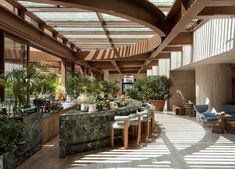 the inside of a restaurant with lots of plants and seating area on either side of the bar