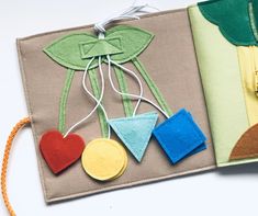 an open book with felt decorations on the front and back cover, along with twine string