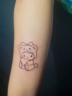 a small tattoo on the arm of a girl with a teddy bear in her lap