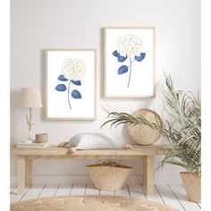 two white flowers are hanging on the wall above a wooden table and wicker baskets