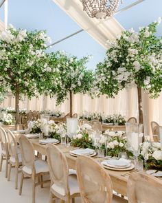 a table set up with white flowers and greenery on the tables for an event