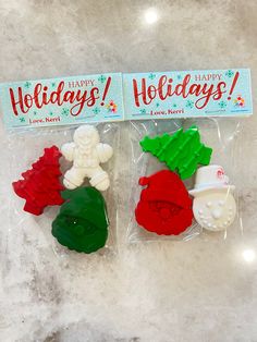 two packaged christmas cookies in plastic bags on a table with a holiday sign above them