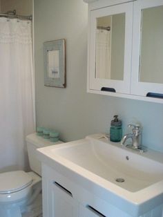 a white bathroom with a sink, toilet and shower curtain is seen in this image