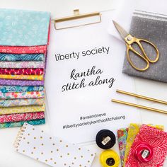 there is a sign that says liberty society next to some fabric and sewing supplies on the table