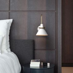 a bed with white sheets and pillows next to a lamp on the side of it