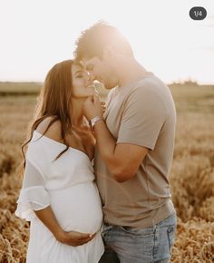 a pregnant couple kissing in a wheat field