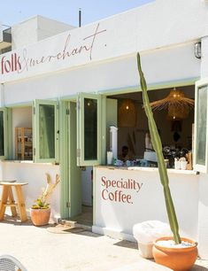 an outside view of a coffee shop with a cactus in the foreground and tables on the other side