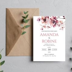 a wedding card with flowers on it next to an envelope