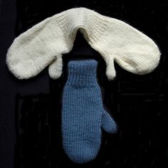 two knit mittens and gloves sitting on top of a black surface with one blue glove