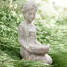 a buddha statue sitting on top of a lush green field