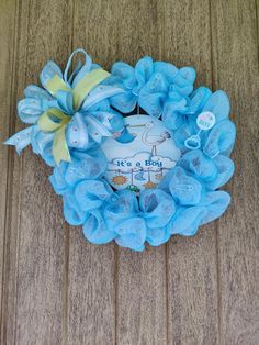 a blue wreath that says it's a boy on top of a wooden floor