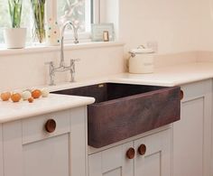 a kitchen with white cabinets and a black sink in it's center, next to a window