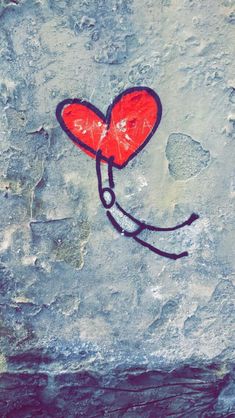 a red heart with a stencil drawn on the side of a cement wall